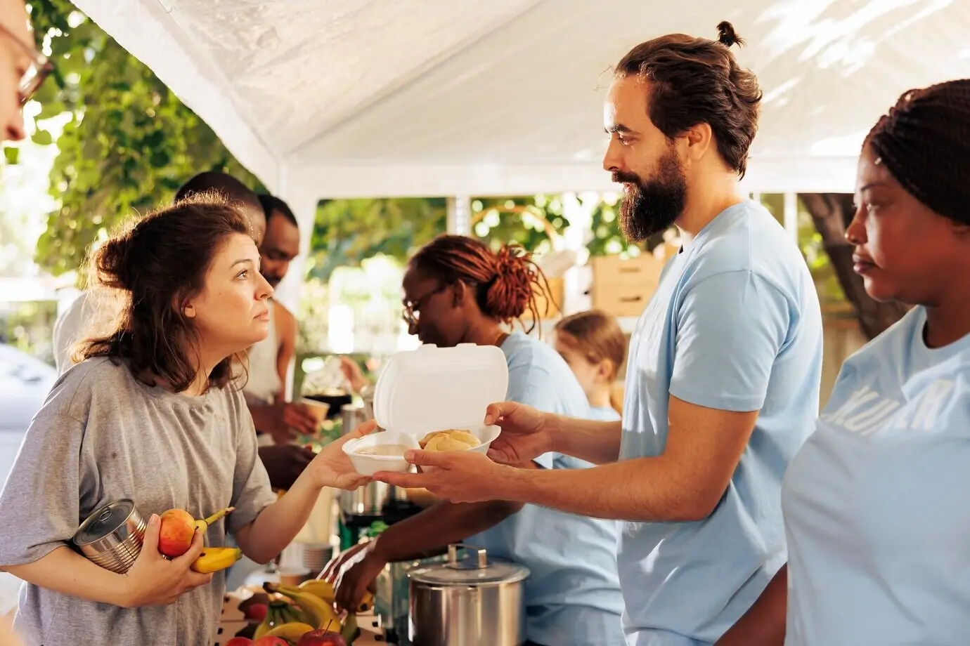 Многонациональная команда гуманитарной помощи оказывает необходимую поддержку нуждающимся: раздаёт еду и помогает в рамках местной некоммерческой инициативы. Молодые волонтёры раздают горячую еду бездомным.